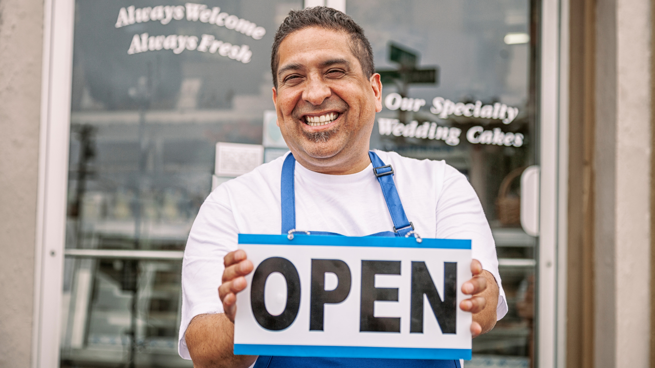 Small business owner holding "OPEN" sign